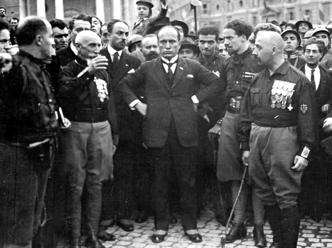 Mussolini seisoo kannattajiensa keskellä.