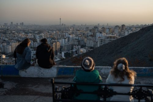Naisia ilman huivia. Taustalla Teheranin siluetti.