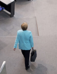 Angela Merkel kävelee laukku kädessään.