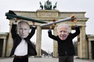 Putiniksi ja Bideniksi pukeutuneet mielenosoittajat pitelevät leikkiohjuksia Brandenburgin portilla.