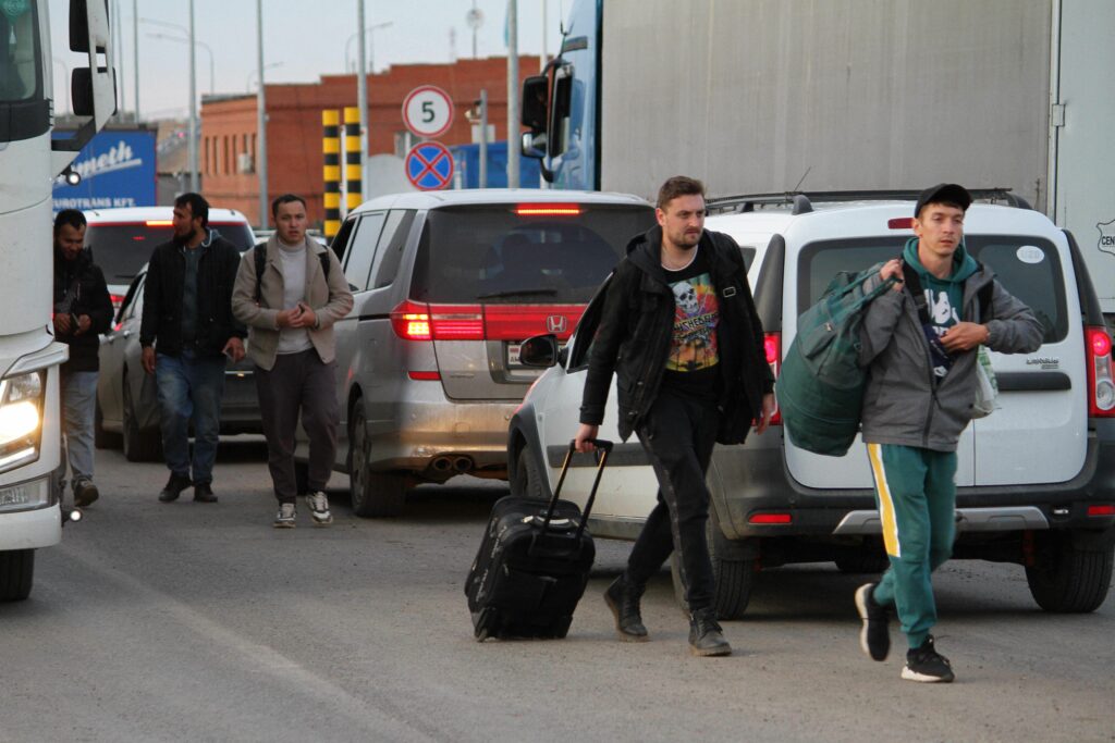 Kaksi venäläistä miestä kävelee autojen välissä Kazakstanin raja-asemalla.